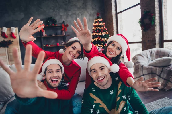 Portrait of group excited positive buddies hands waving hi new year greeting decorated apartment indoors.