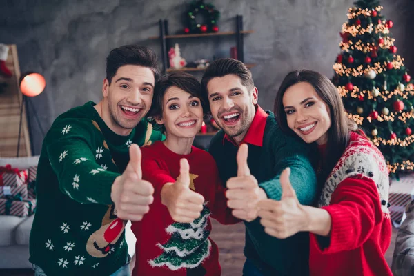 Portrait of funky friendly people have fun enjoy christmas event demonstrate thumb up decorated house indoors.