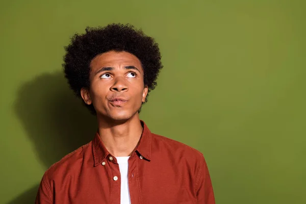 Photo of minded puzzled man with afro hairstyle dressed brown shirt look at proposition empty space isolated on khaki color background.