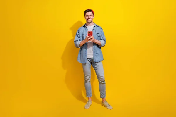 陽気なクールな男のフル長さの写真はデニムジャケットチャットInstagramのテレグラムFacebookの隔離された黄色の背景を着用します — ストック写真