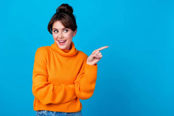 Photo of excited funky lady wear knitted pullover looking showing finger empty space isolated blue color background.