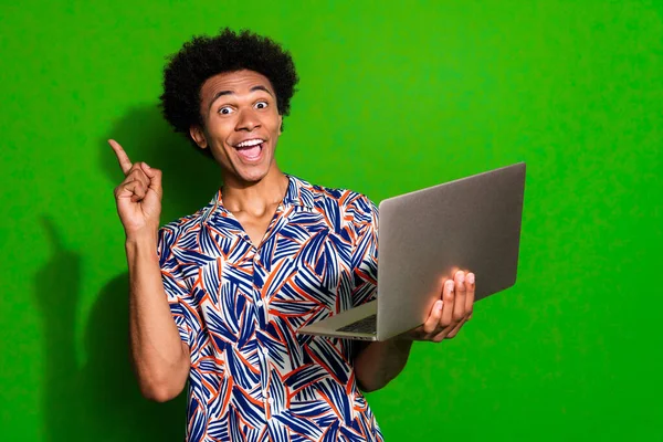 Photo of crazy funky man dressed print shirt pointing finger working modern gadget empty space isolated green color background.