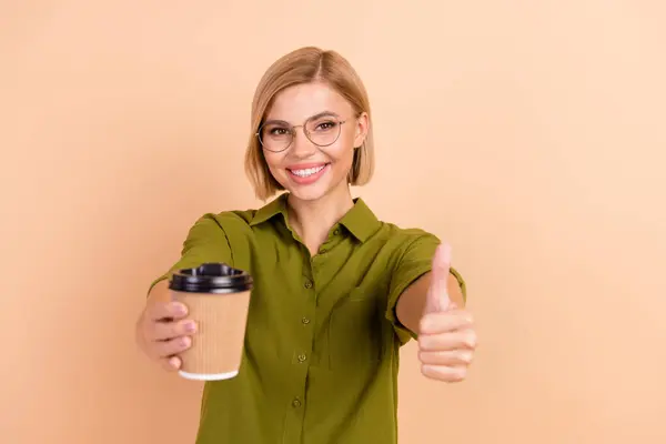楽観的な快適な女性の写真 グラスに緑のシャツを着て ベージュ色の背景に隔離されたコーヒーショーのカップを保持 — ストック写真