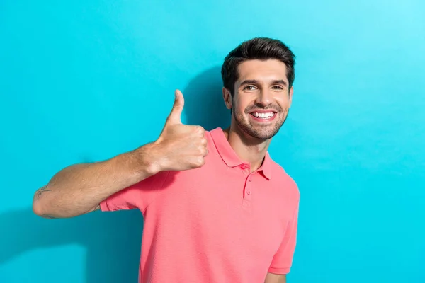若いハンサムモデル男ブルネット髪の肖像画 ピンクのTシャツを着用 アクアマリンカラーの背景に隔離された高いレートシンボル — ストック写真