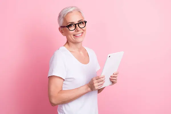照片上的成功女性 留着短发 戴着白色的T恤 手持平板电脑 阅读着与粉色背景隔离的电子邮件 — 图库照片