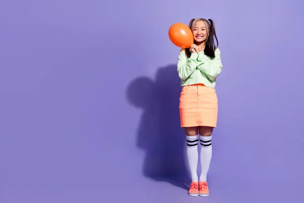 Full length photo of korean model youngster smile girl holding air balloon near copy space sale banner isolated on purple color background.