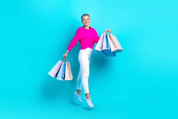 stock image Full length photo of cheerful nice person arms hold store bags jumping isolated on teal color background.