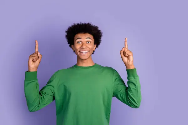 興奮する陽気な男の写真 緑のプルオーバーを着用 つの指を指して空のスペースを隔離された紫色の背景 — ストック写真