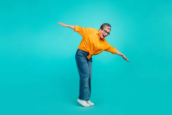 Full size photo of keep balance old woman falling into abyss dangerous tightrope wear orange shirt jeans isolated on blue color background.