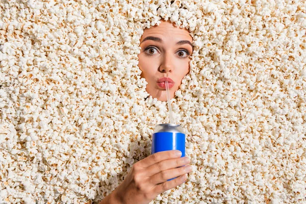 Top view portrait of funky lady hand hold cola pepsi soda drink can sipping straw face isolated on pop corn background.