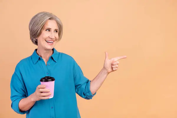 Portrait of funny person wear blue shirt hold takeaway cup look directing at coffee store empty space isolated on pastel color background.