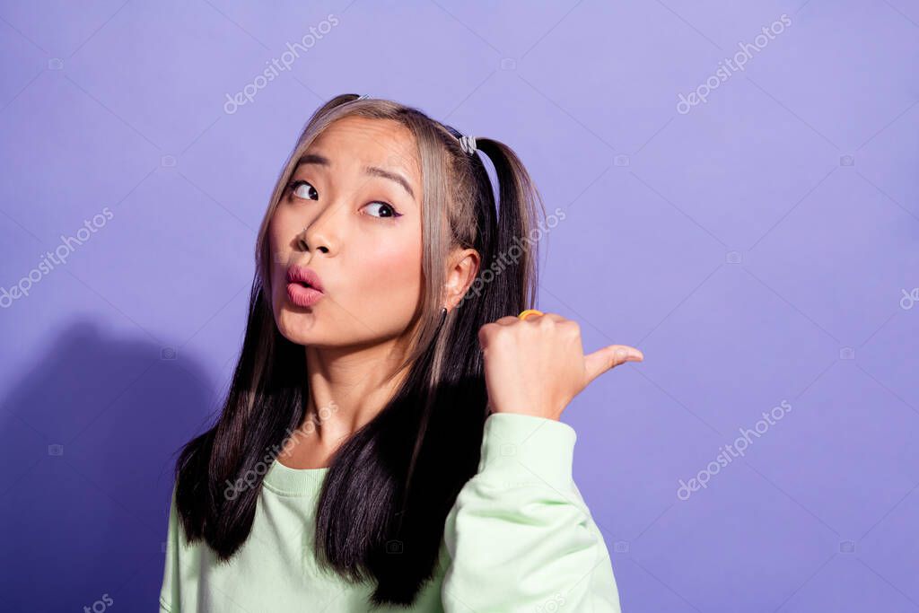 Photo of astonished woman with dyed hair wear sweatshirt staring indicating at discount empty space isolated on purple color background.
