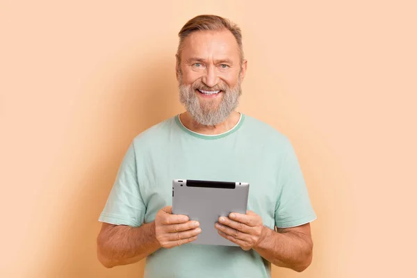 インテリジェントな満足の退職した男の肖像画は スタイリッシュなTシャツのホールドタブレットは パステルカラーの背景に分離された電子ブックを読みます — ストック写真