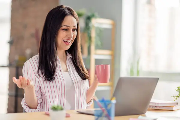 快乐企业家的画像女孩手持咖啡杯与室内视频通话笔记本电脑写字台 — 图库照片