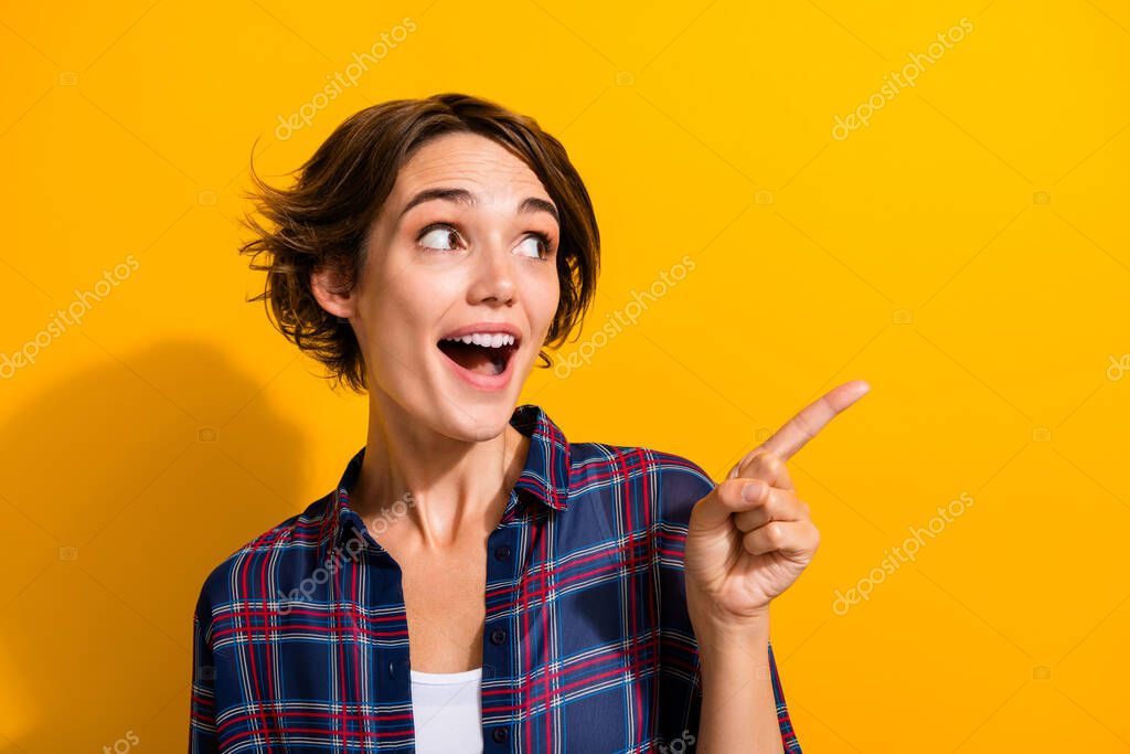 Photo of impressed woman with bob hairdo dressed plaid shirt look directing at sale empty space isolated on yellow color background.