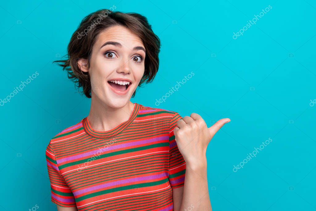 Photo of impressed ecstatic woman dressed striped t-shirt directing at discount empty space isolated on turquoise color background.
