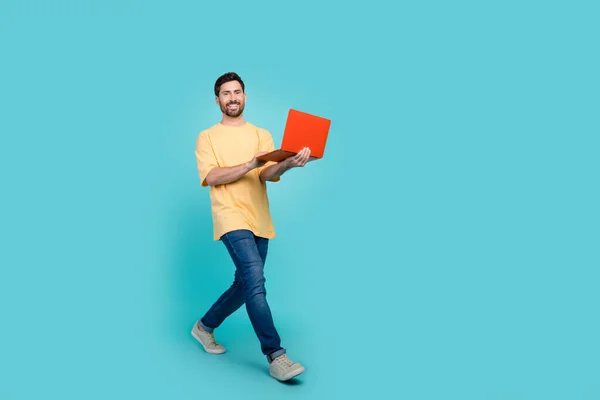 Full body size photo of young brunet guy in casual outfit walking with notebook buying something online isolated on cyan color background.