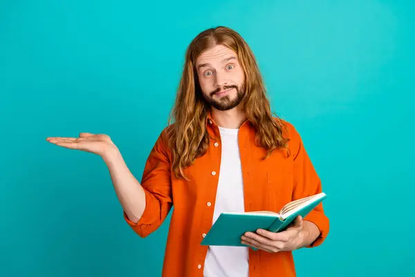 Photo of smart guy with wavy hairdo wear stylish outfit hold book palm demonstrate sale empty space isolated on turquoise color background.