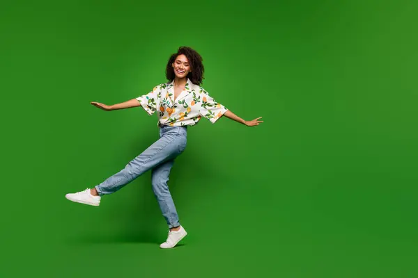 兴奋而时髦的女人穿着印花衬衫跳舞的全长照片 空旷的空间孤立的绿色背景 — 图库照片