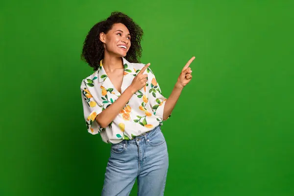 Photo of pretty thoughtful woman dressed print shirt looking pointing two fingers empty space isolated green color background.