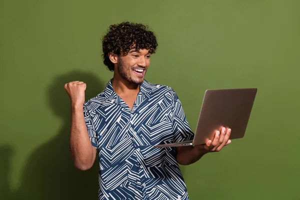 Photo of impressed lucky man dressed print shirt winning game modern gadget empty space isolated green color background.