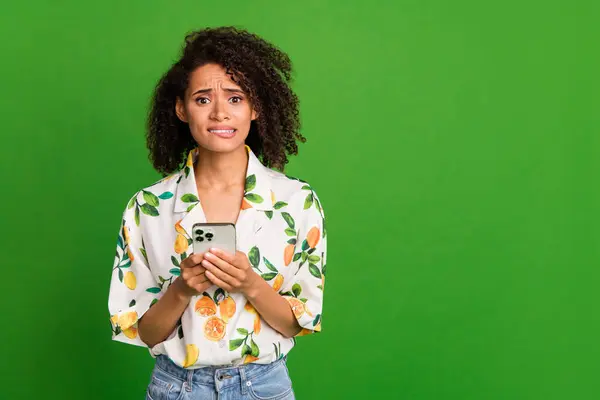 Photo of uncertain stressed woman dressed print shirt communicating modern gadget empty space isolated green color background.