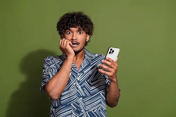 Photo of funky scared man dressed print shirt communicating modern gadget empty space isolated green color background.