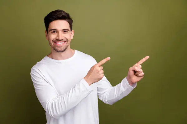 Portrait of positive friendly person toothy smile indicate fingers empty space offer isolated on khaki color background.