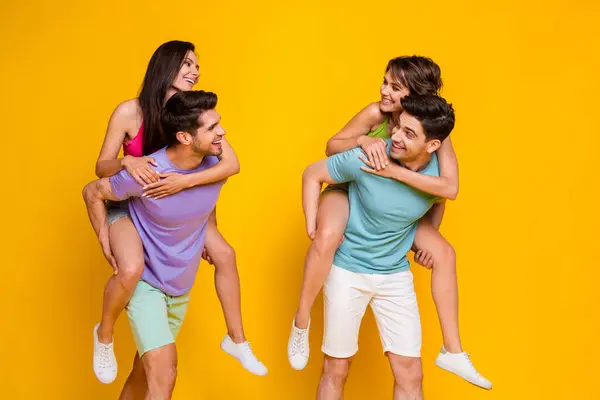 Photo of four people fellows have free time together speaking guy piggyback girls isolated bright color background.