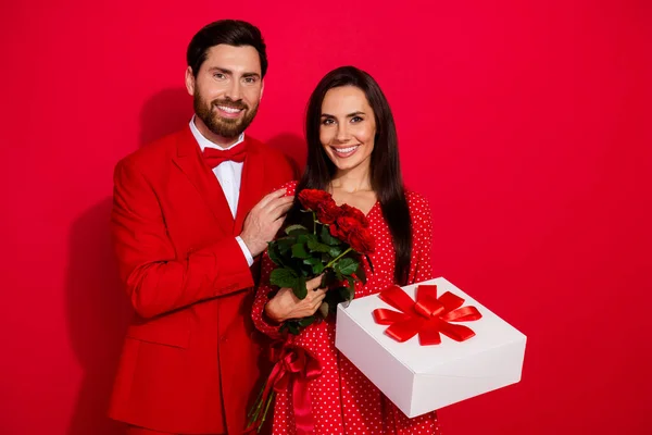 年轻貌美的情侣抱着情人节的照片 穿着时尚典雅的衣服 背景为红色 — 图库照片