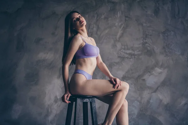 紫色の下着の支配女性のレタッチ写真は 灰色の壁の背景の上に服なしで木製の椅子に座っていません — ストック写真