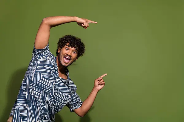 Portrait of hispanic crazy guy in trendy shirt point fingers empty space recommendations to save money isolated on khaki color background.