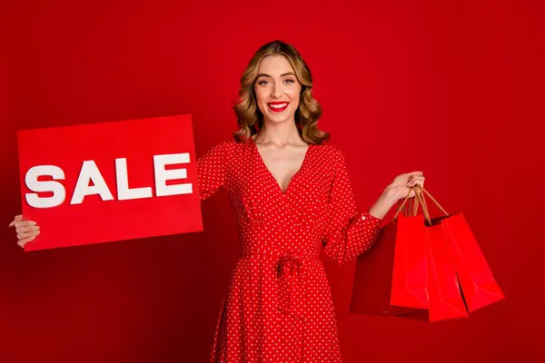 照片上快乐可爱的女孩笑着拿着销售贺卡商场的购物袋 用鲜红的背景把它们隔开 — 图库照片