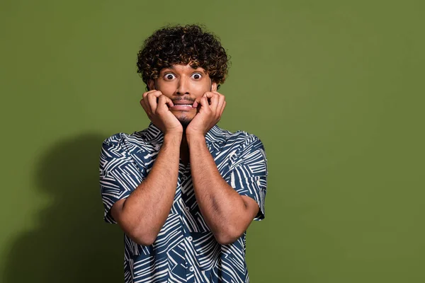 Photo of scared frightened man dressed print shirt hands arms cheeks cheekbones empty space isolated green color background.