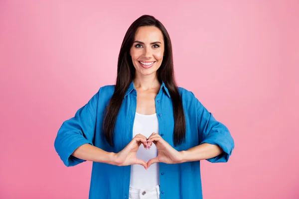 Portrait of kind sincere woman with straight hair wear stylish clothes fingers showing heart symbol isolated on pink color background.