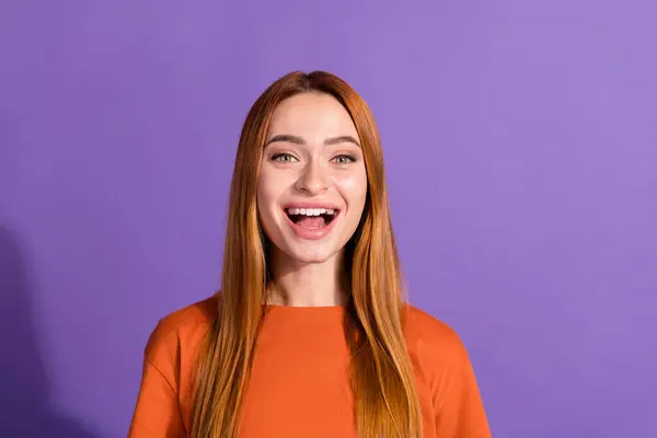Portrait of young funny laughing pretty woman red hair model in orange t shirt have fun surprises isolated on violet color background.