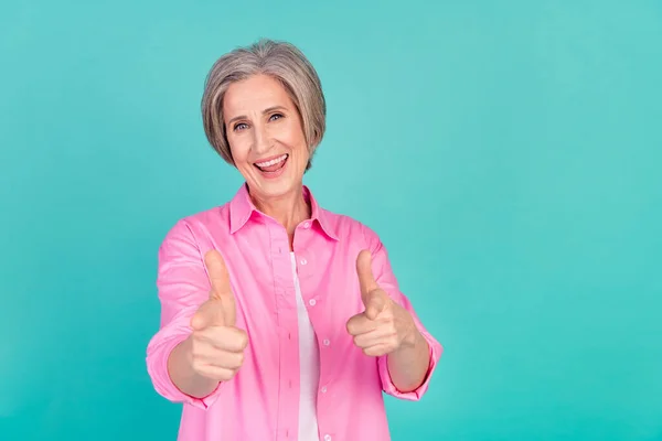 穿着粉色时髦衬衫的老奶奶的画像 她用食指前移 用青色背景向你打招呼 — 图库照片