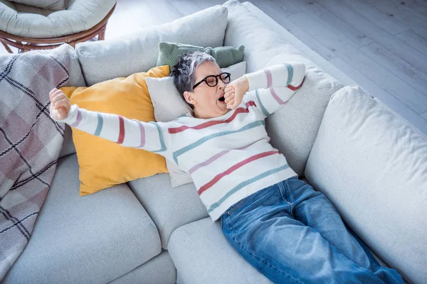 High angle view photo of exhausted aged person lying couch hand cover mouth yawning pastime house inside.