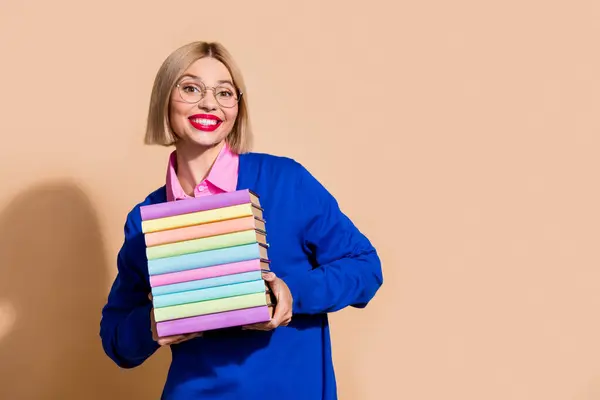 Photo of charming excited person beaming smile hold pile stack book empty space isolated on beige color background.