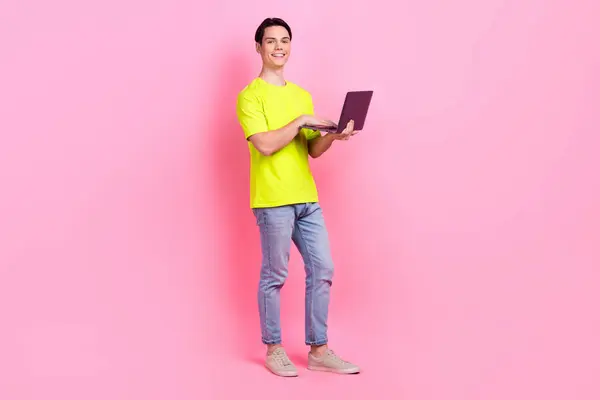 照片全长 开朗而兴奋的男人穿着黄色T恤发短信给现代设备孤立的粉色背景 — 图库照片