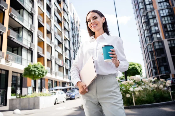 Photo of successful lovely lady dressed stylish white shirt glasses hand hold espresso latte modern netbook going home weekend holidays.