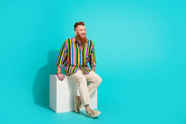 Full body size photo of handsome model irish man sitting on platform daydreaming looking copyspace isolated over cyan color background.