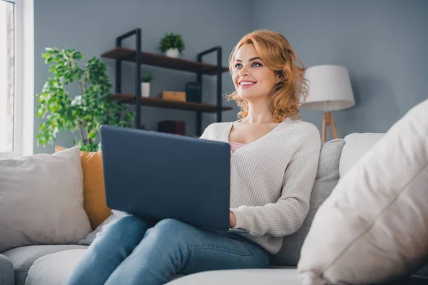 Portrait of cheerful lovely lady sitting comfy sofa use laptop brainstorming free time apartment inside.
