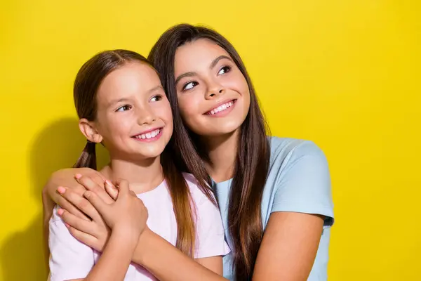 興奮した思慮深い小さな姉妹の写真は 空のスペースを隔離された黄色の背景を見ながらカドリングTシャツを着ます — ストック写真