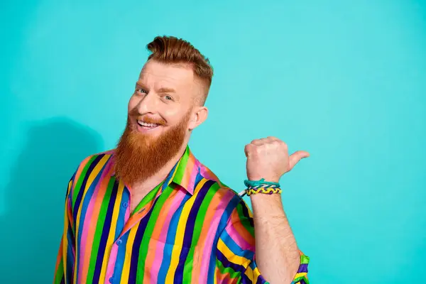 Photo of red hair bearded mustache man in striped shirt point thumb empty space give advice for beginners isolated on cyan color background.