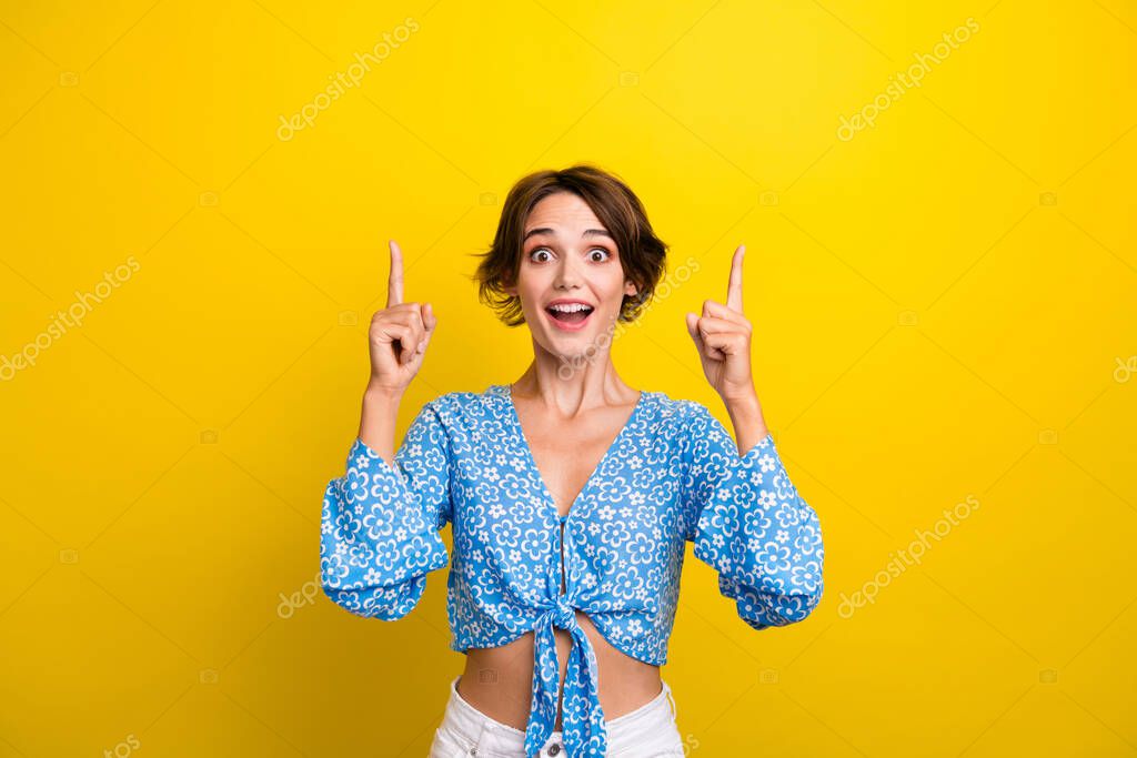 Photo of impressed funky woman wear flower print blouse showing two fingers empty space isolated yellow color background.