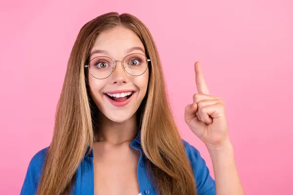 Photo of excited funky lady dressed blue shirt eyewear pointing finger up empty space isolated pink color background.
