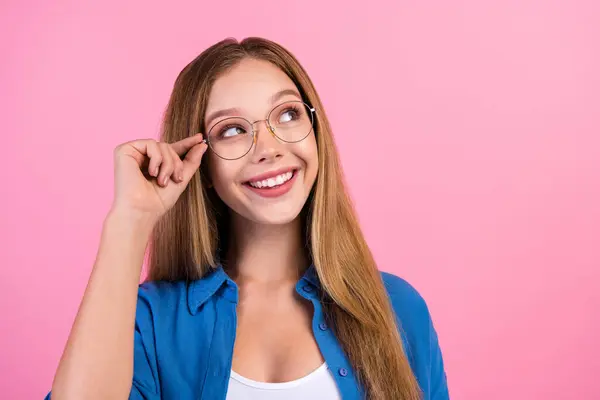 Photo of dreamy excited lady dressed blue shirt arm eyewear looking empty space isolated pink color background.
