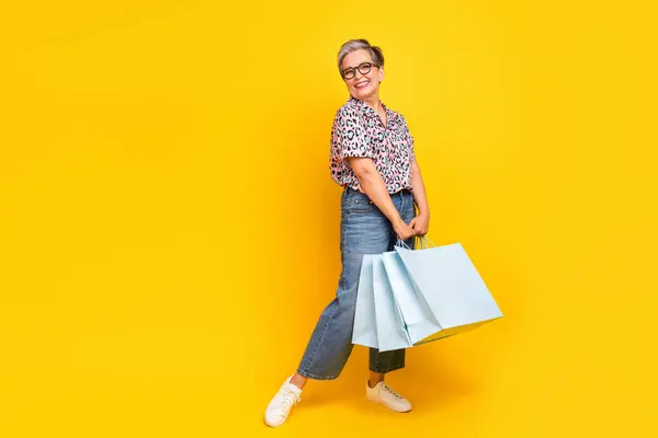 漂亮的退休女性购物袋大减价服装时尚豹纹装束的全长照片 以黄色为背景 — 图库照片