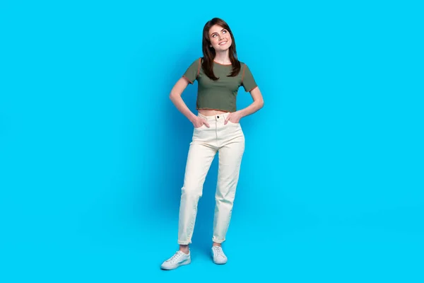 Full body portrait of minded positive lady put arms pockets look empty space isolated on blue color background.